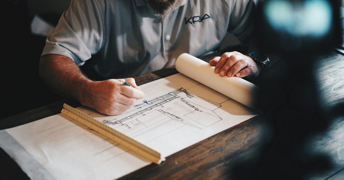 Planos arquitectónicos y herramientas sobre una mesa de trabajo